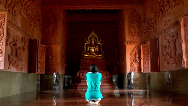Mujer-orando-delante-de-la-estatua-de-Buda-en-templo-budista
