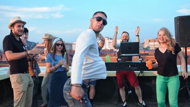 Male-hip-hop-dancer-in-sunglasses-modern-dancing-at-summer-rooftop-party