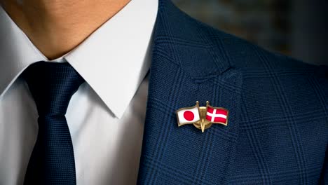 Businessman-Walking-Towards-Camera-With-Friend-Country-Flags-Pin-Japan---Denmark