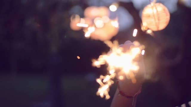 slow-motion-shot-of-young-woman-lighting-sparklers-in-garden