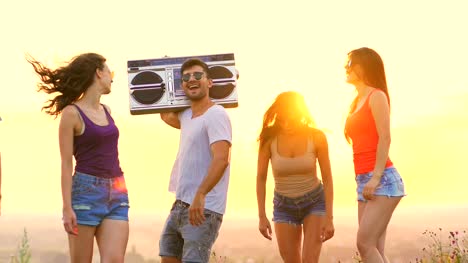 The-people-with-a-boom-box-dancing-on-the-sunset-background.-slow-motion