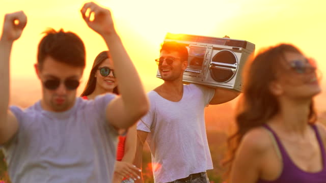The-happy-people-with-a-boom-box-dancing-on-a-sun-background.-slow-motion