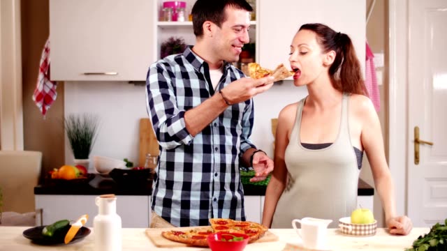 Boyfriend-feeding-pizza-to-Girlfriend-at-home