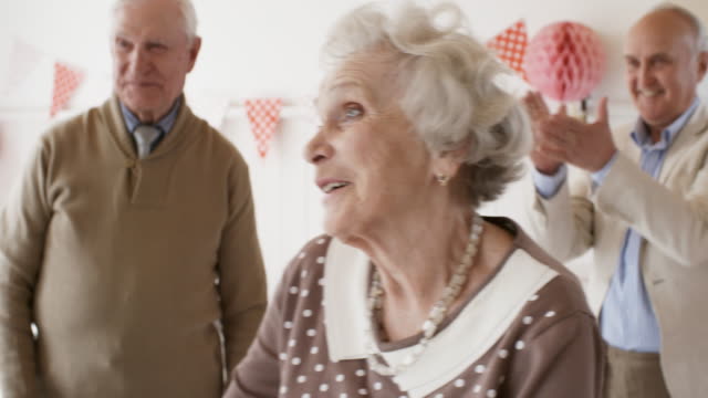 Smiling-Senior-Woman-Embracing-Male-Friend-at-Birthday-Celebration