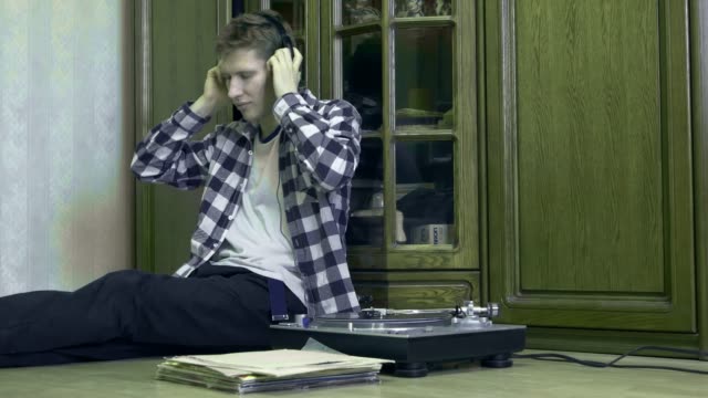 portrait-of-young-man-at-home-listening-to-the-vinyl-records,-relaxing-and-dreaning