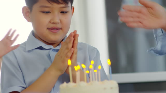 Asia-muchacho-soplando-las-velas-en-el-pastel-de-cumpleaños