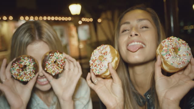 Retrato-de-dos-niñas-lindas-divertirse-haciendo-muecas-con-los-donuts-sobre-ojos