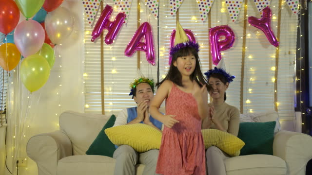 Happy-asian-father-and-mother-looking-at-their-daughter-dancing-happily.-Asian-family-with-happy-time-at-home.