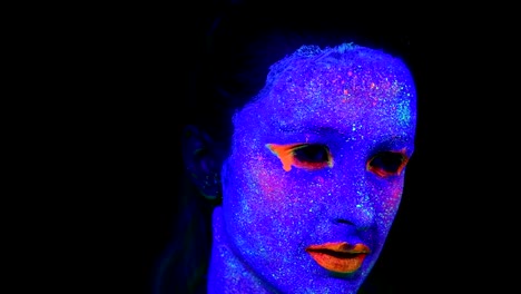 Woman-with-UV-face-paint,-glowing-clothing-portrait,-hand-touching-face,-close-up-of-make-up.-Caucasian-woman.-.