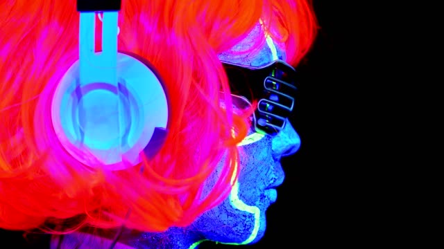 Mujer-con-pintura-Ultravioleta-de-la-cara-de-cyborg,-peluca,-brillantes-gafas,-ropa-con-auriculares-cerca-cara-tiro.-Mujer-asiática.-.