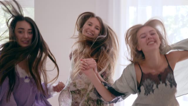 freudige-Gefühle,-glückliche-junge-Frauen-springt-Spaß-auf-Bett-während-der-Pyjamaparty-in-Zeitlupe
