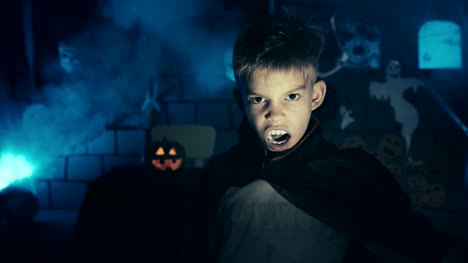 Kleiner-Junge-in-einem-Vampir-Kostüm-für-Halloween-mit-seiner-Furcht-einflössenden-Gesicht-und-Zähne-zu-Kamera