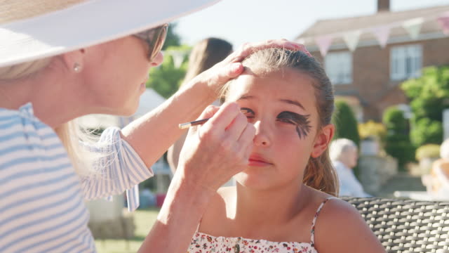 Woman-face-painting-girl-at-English-summer-garden-fete---shot-in-slow-motion