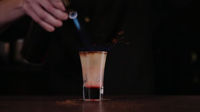 Der-Barkeeper-ist-einen-Cocktail-aus-Feuer.-Hiroshima-cocktail.-Das-Barkeeper-zündet-das-Feuerzeug-in-der-Leiste