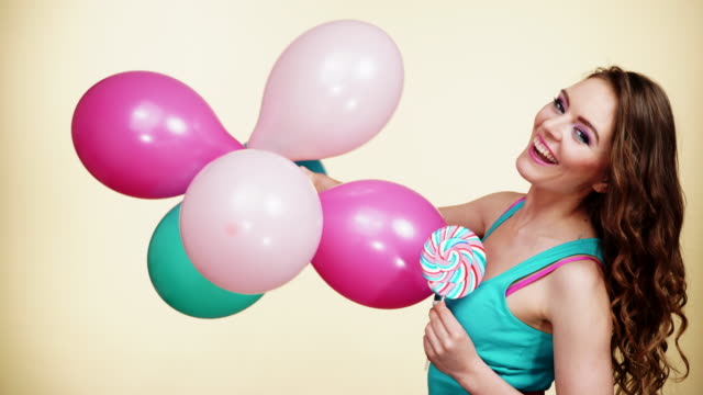 Frau-lächelndes-Mädchen-mit-bunten-Luftballons-und-Lollipop-4K