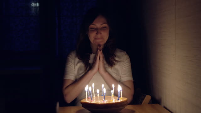 Young-woman-blowing-out-candles-on-holiday-cake