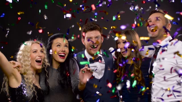 happy-friends-at-party-under-confetti-over-black