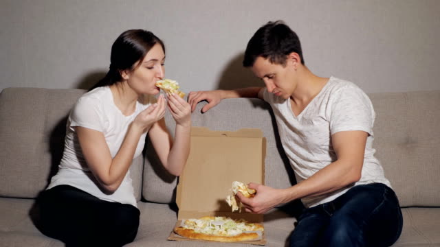 Hermosa-joven-pareja-en-ropa-casual-está-comiendo-pizza