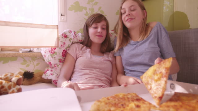 Girl-joking-and-feeding-her-friend-huge-slice-of-pizza