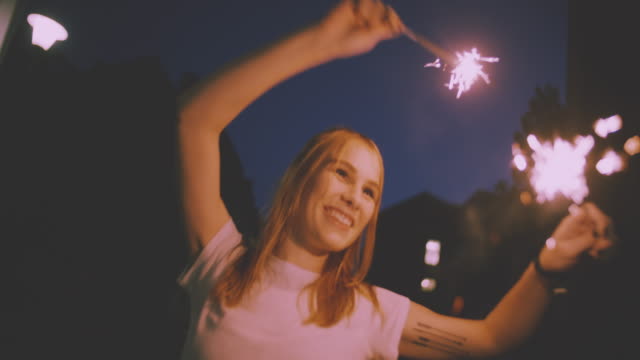 Sonriendo-teenage-girl-on-the-street-at-night-with-sparklers