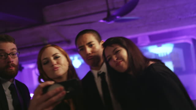 Eine-Gruppe-von-gut-gekleidete-Freunde-in-einem-Nachtclub-unter-Selfies-mit-einem-Handy