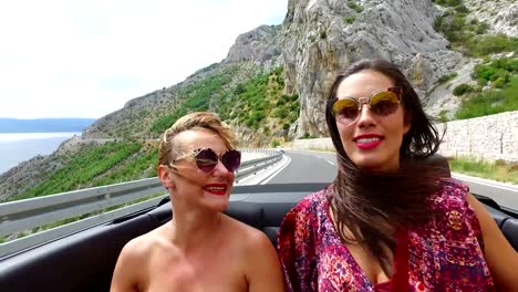 Two-happy-girls-partying-while-riding-in-cabriolet