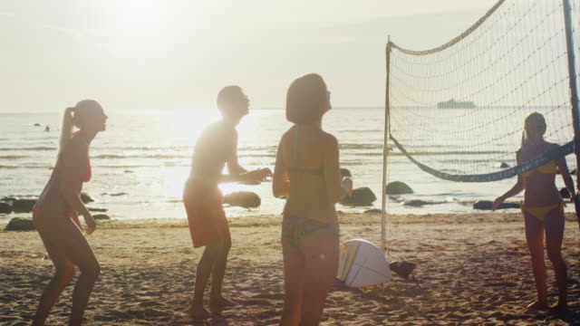 Grupo-de-jóvenes-jugando-al-voleibol-de-playa-en-Sunset-Light.-Cámara-lenta-60-FPS.