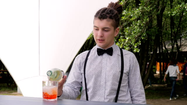 bartender-makes-mixed-drink-on-background-nature,-bar-worker-topped-up-rom-into-glass-with-ice-cubes