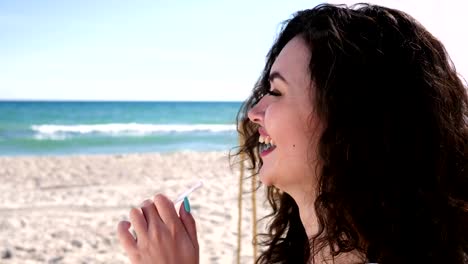 portrait-happy-woman-with-curly-hair-on-beach,-female-gesture-hello,-woman-drinks-cocktail-Through-straws-and-rest,-summer-season