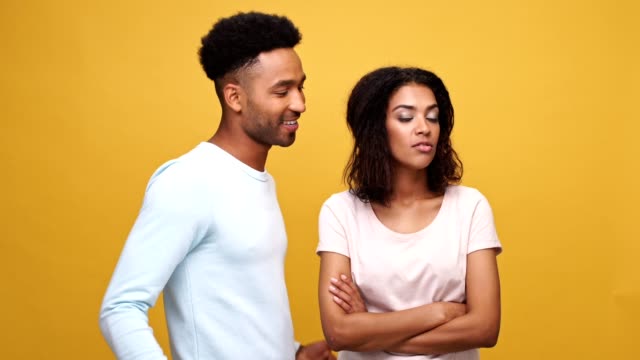 Zuversichtlich-jungen-afrikanischen-Mann-versucht-zu-Fragen,-eine-hübsche-Frau,-für-ein-Datum-über-gelbem-Hintergrund-isoliert