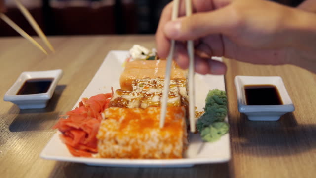 Gente-comiendo-rollos-en-bar-restaurant-o-sushi-de-Japón