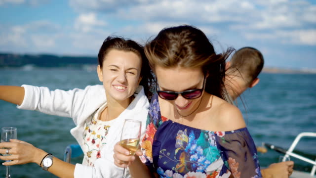 Kleine-Gruppe-von-Freunden-auf-der-Yacht,-laut-lachend-und-Segeln-das-Meer-Champagner-trinken-feiern