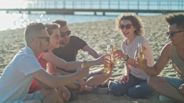 Junge-Menschen-klirrende-Flaschen-am-Strand