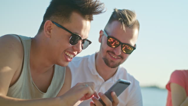 Young-People-Having-Fun-on-the-Beach-Using-Phones