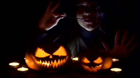 Halloween-Hexe-mit-einer-Magie-Kürbis.-Schöne-junge-Frau-in-Hexen-Hut-und-Kostüm-mit-geschnitzten-Kürbis.-Halloween-Art-design