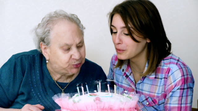 Glückliche-Großmutter-feiert-ihre-Geburtstagstorte-mit-ihrer-Enkelin