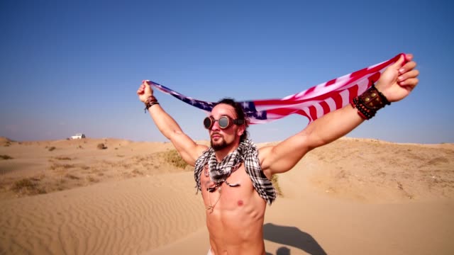 Mann-mit-Steampunk-Brille-und-amerikanische-Flagge-laufen-in-Wüste