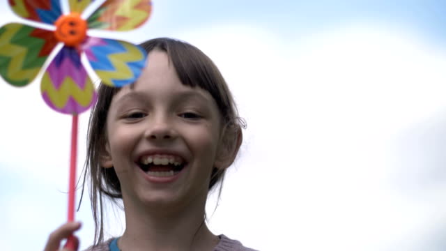 schöne-Mädchen-mit-Windmühle-Spielzeug-auf-die-Natur-lächelt-und-schaut-in-die-Kamera
