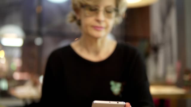 Eine-Frau-mittleren-Alters-nutzt-Mobile-Telefone-in-einem-Café.