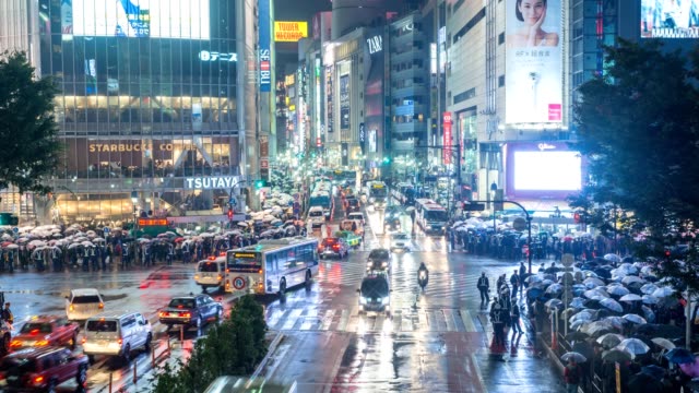Night-timelapse-of-tourist-with-umbrella-walking-at-Shibuya-crossing-street-intersection,-Shibuya,-Tokyo,-Japan-4K-time-lapse