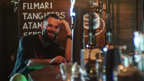 Bearded-guy-drinks-a-cocktail-and-communicates-with-the-bartender-at-the-bar-counter-in-4k-resolution-in-slow-motion