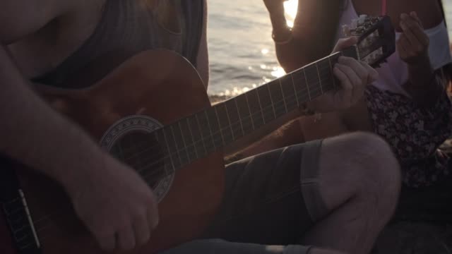 Hombre-tocando-guitarra-para-amigos-en-la-playa