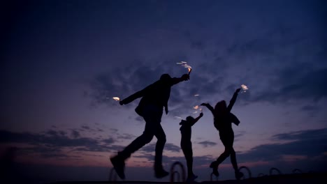 Feiernde-Jugendliche-genießen-ihre-Zeit-zusammen-mit-Feuerwerk-nach-Sonnenuntergang