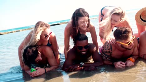 Young-multi-ethnic-friends-at-the-beach-lying-in-the-water