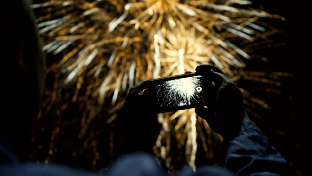 Silhouette-eines-Mannes-fotografieren-Feuerwerk-am-Nachthimmel.-Schönen-Gruß-zu-Ehren-des-Feiertags