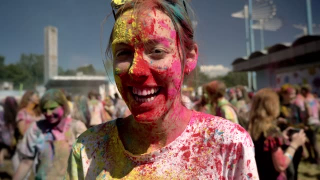Young-happy-girl-in-colourful-powder-is-laughing-on-holi-festival-in-daytime-in-summer,-color-concept