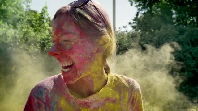 Young-happy-girl-is-thrown-with-yellow-powder-on-holi-festival-in-daytime-in-summer,-laughing,-color-concept