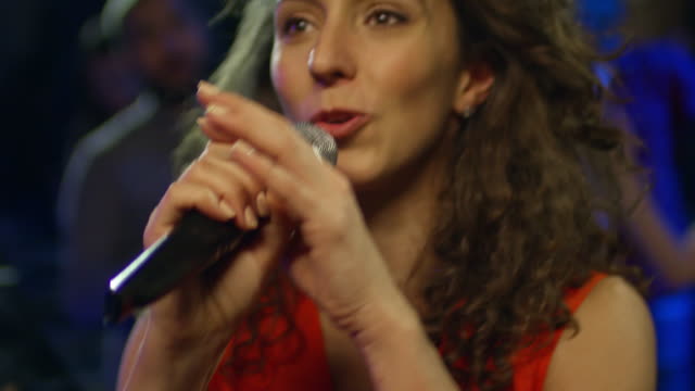 Lockig-behaarte-Frau-singen-Karaoke