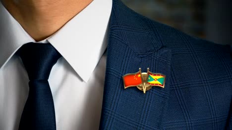 Businessman-Walking-Towards-Camera-With-Friend-Country-Flags-Pin-China---Grenada