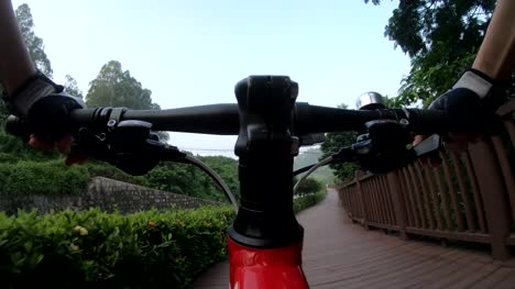 Montar-bicicleta-en-la-Ciclovía-en-el-parque,-vista-desde-la-perspectiva-en-primera-persona-POV---punto-de-vista-frontal-por-cámara-de-acción